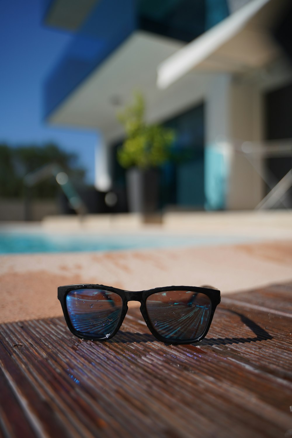 Foto de gafas de sol Wayfarer grises con monturas negras sobre superficie de madera marrón