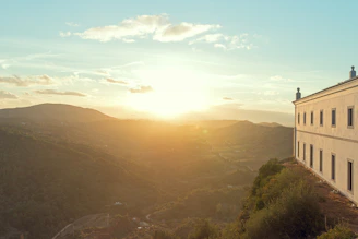 A stately Texas Hill Country estate bathed in warm sunset light with rolling hills in the background.