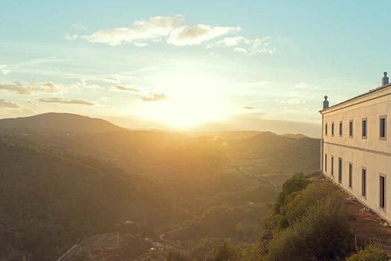 A stately Texas Hill Country estate bathed in warm sunset light with rolling hills in the background.
