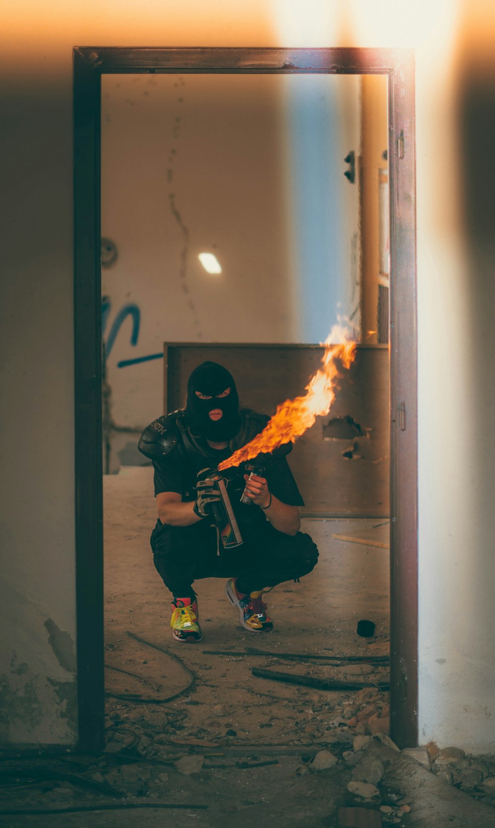 homem usando máscara de gorro preto segurando garrafa de spray de fogo