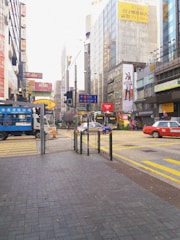 A busy city street with a car wrapped in a colorful stick2earn advertisement.