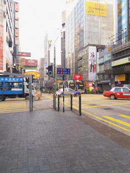 A busy city street with a car wrapped in a colorful stick2earn advertisement.