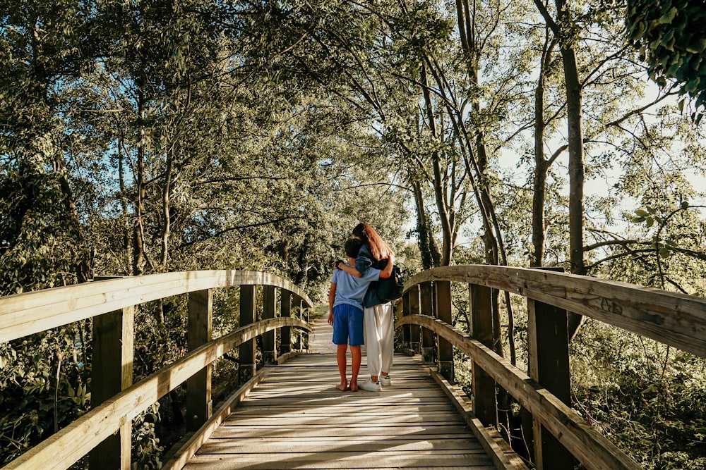 woman wearing black blouse and white pants walking on brown wooden bridge