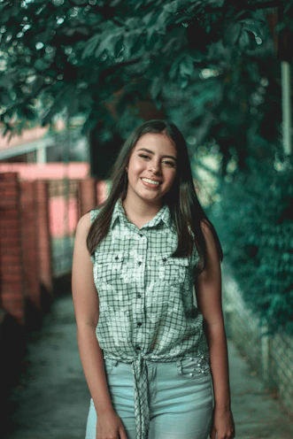 A young woman wearing a casual streetwear shirt with relaxed fit, smiling in a sunny street.