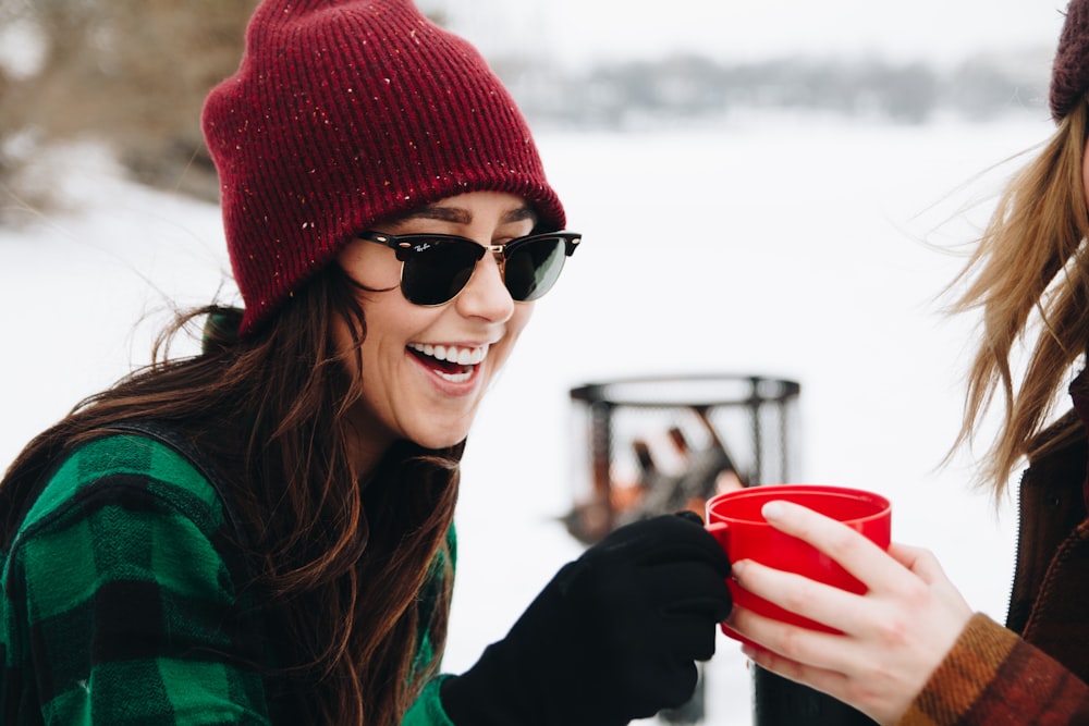 woman wearing red knitted beanie holding red plastic cup