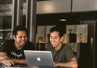 two smiling men looking at MacBook