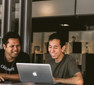 two smiling men looking at MacBook
