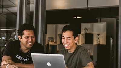 two smiling men looking at MacBook