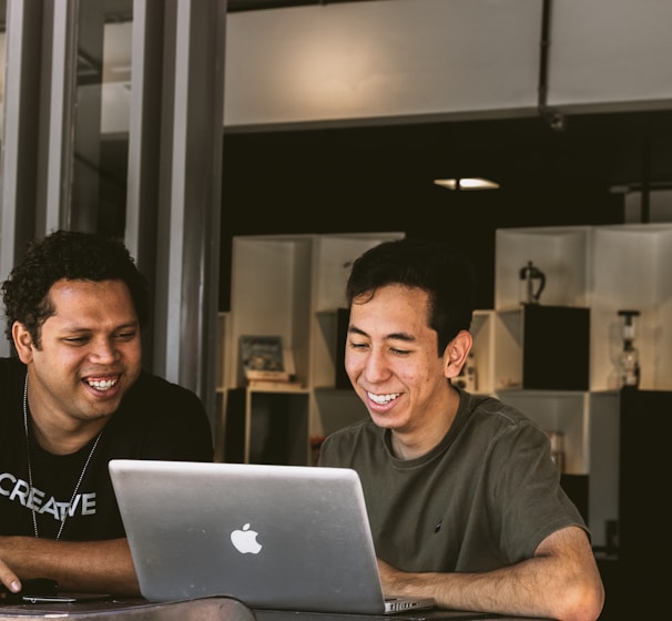 two smiling men looking at MacBook