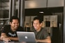 two smiling men looking at MacBook
