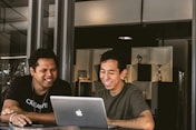 two smiling men looking at MacBook