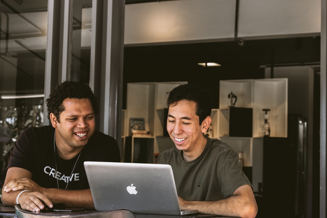 Two employees looking at a laptop with a smile on their face.