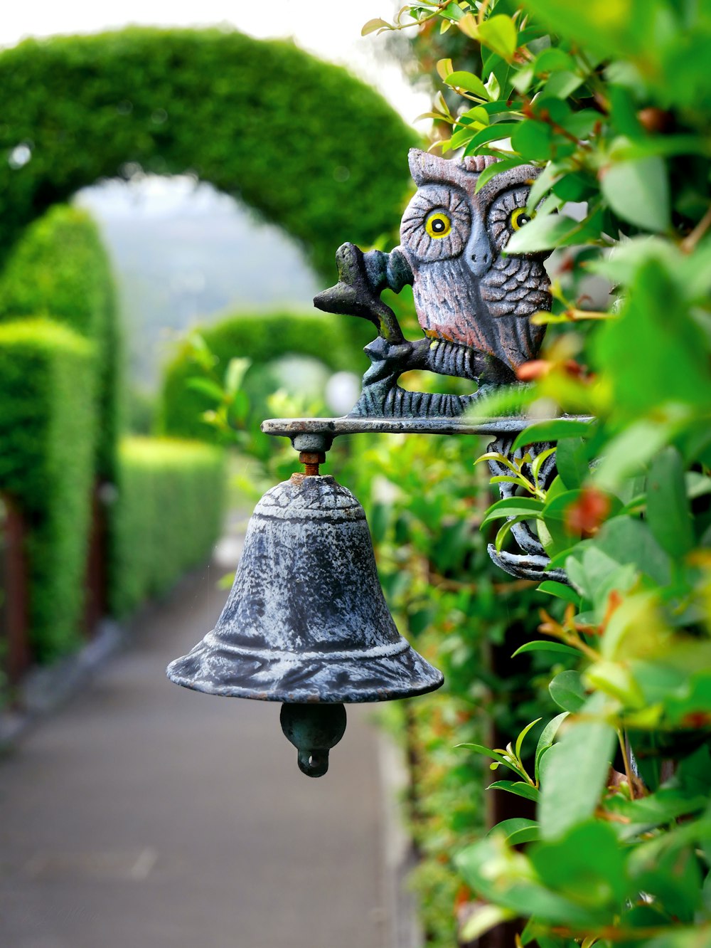 grey metal bell on hedge