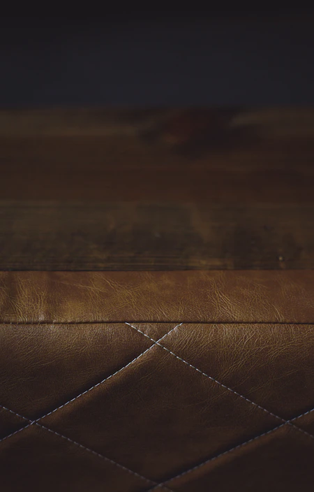 Close-up of textured quilt patterns in warm earth tones layered on a rustic wooden bed frame.