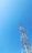 A tall communication tower stands against a clear blue sky. The tower features alternating sections of red and white and is equipped with several antennas.