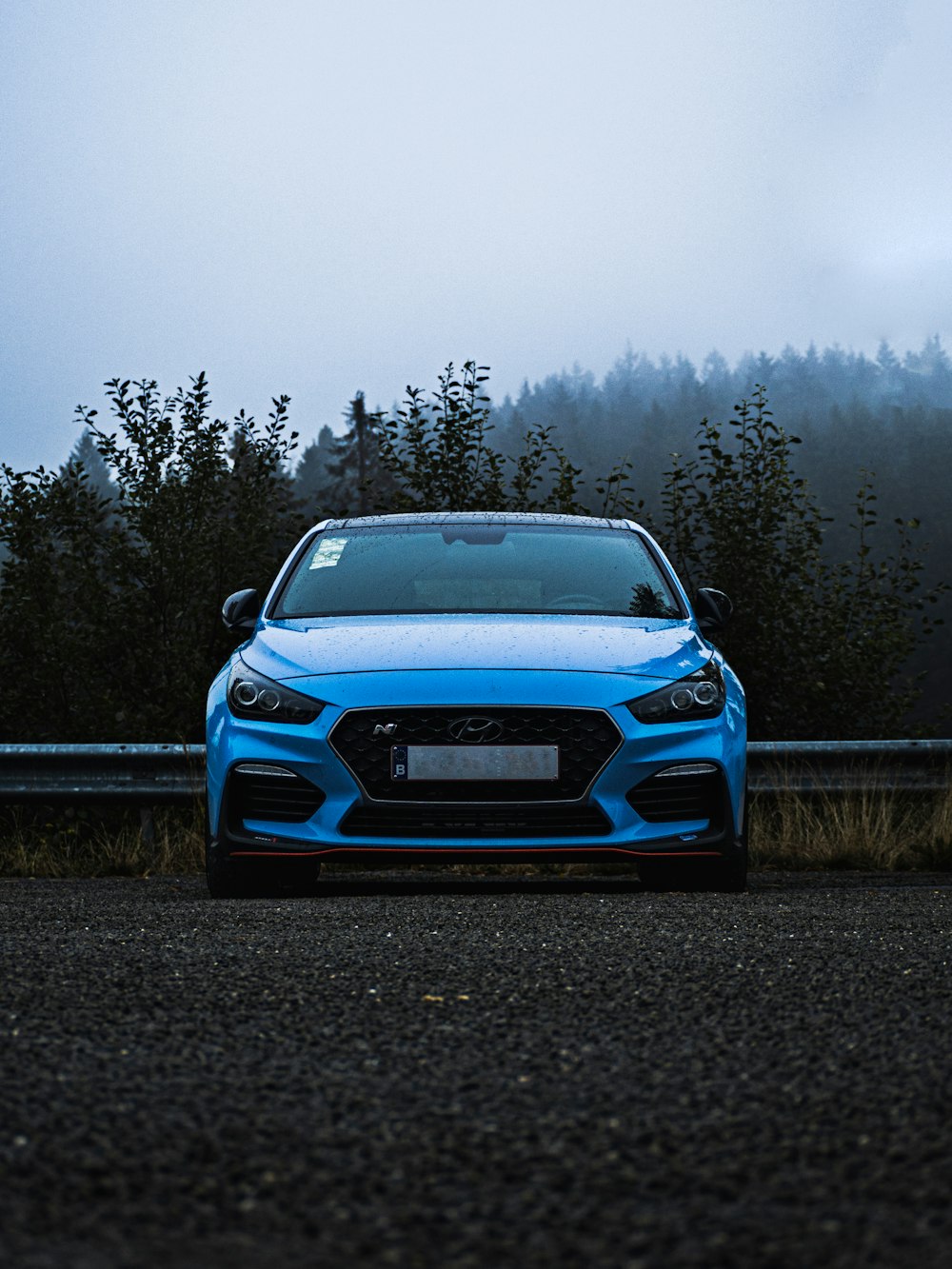 blue Hyundai car parked near tree