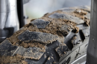 Close-up of a dirt bike tire kicking up mud on a trail.