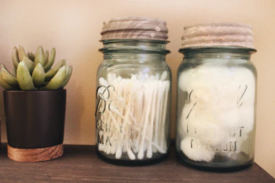 Elegant glass jar filled with cotton balls on a clean beige vanity.