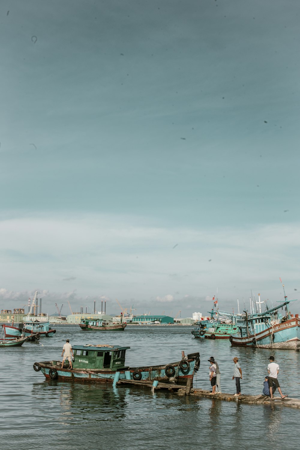 people standing on wooden docks besides blue and green boat