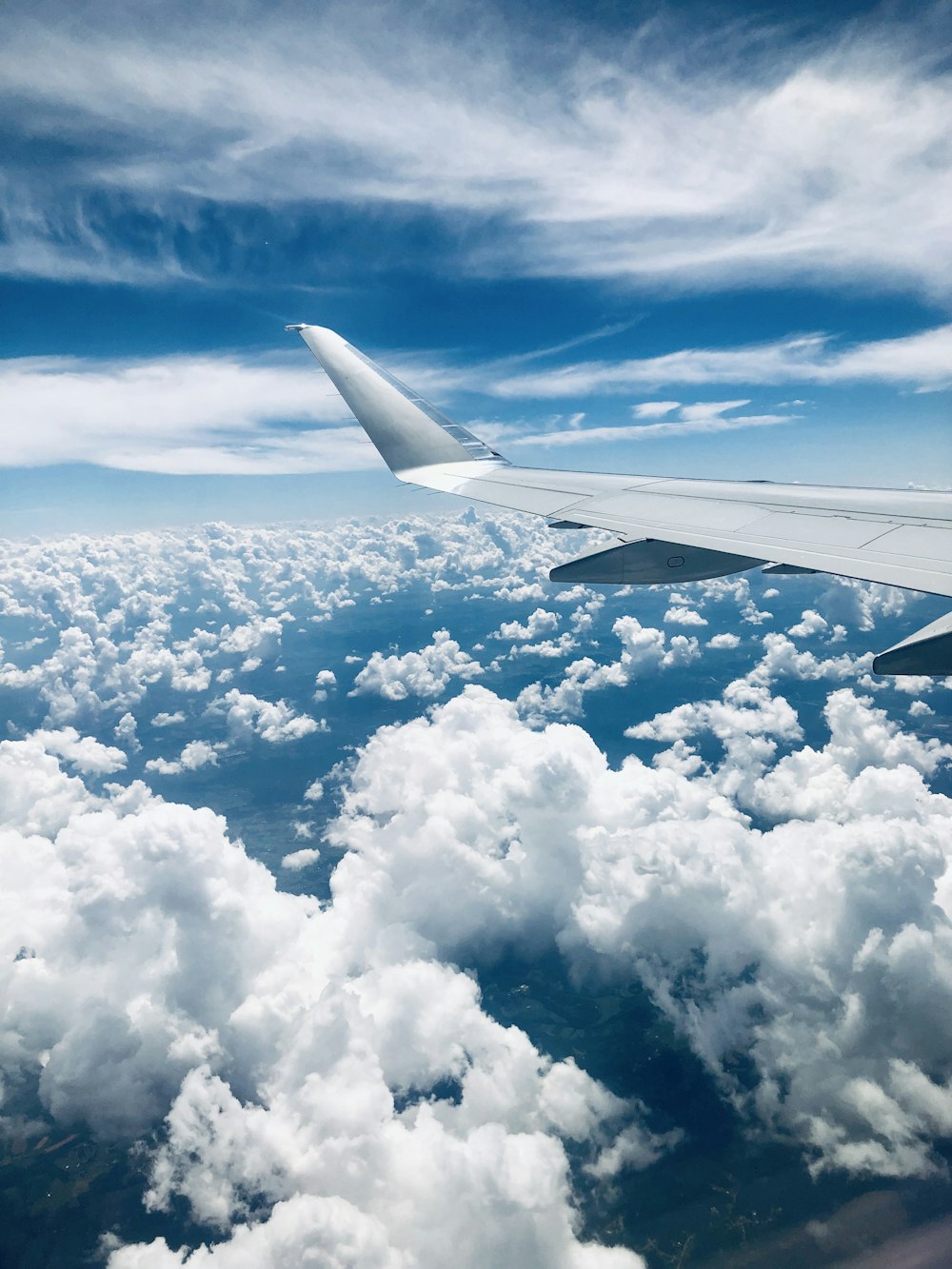 airplane wing across clouds photo during daytime