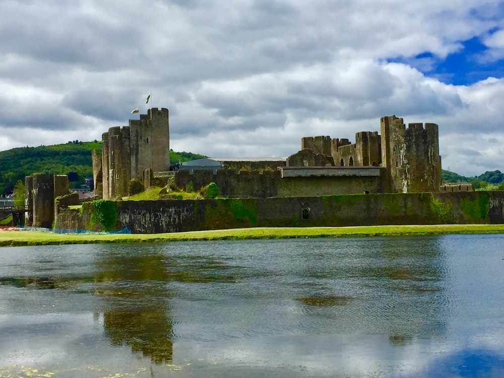 ancient castle facing body of water under cloudy sky