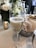 A champagne flute filled with sparkling wine is placed on a table set for a formal event. In the foreground, a candle in a small holder adds to the elegant ambience. Surrounding the glass are white flowers in a bouquet and a neatly folded napkin beside a decorative bowl.
