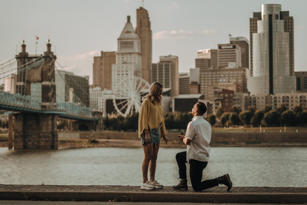 man kneeling in front of woman during daytime