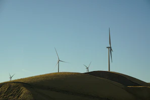 Wide shot of a wind turbine farm with clear blue sky in the background