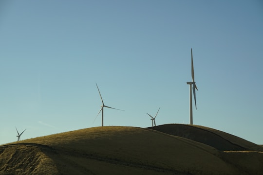 Wind turbines spinning in a vast landscape under a clear blue sky.