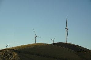 Wide shot of a clean energy wind farm under a clear blue sky.