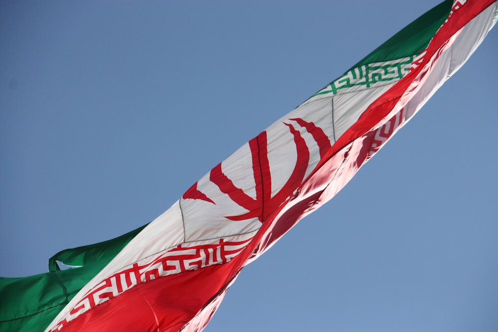 two flags flying in the wind with a blue sky in the background