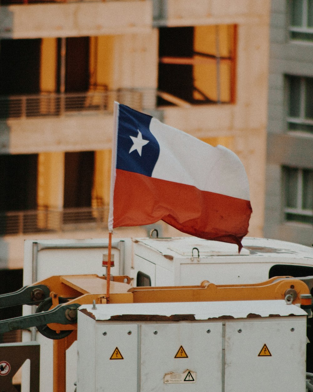 selective focus photography of raised flag on white and yellow machine during daytime