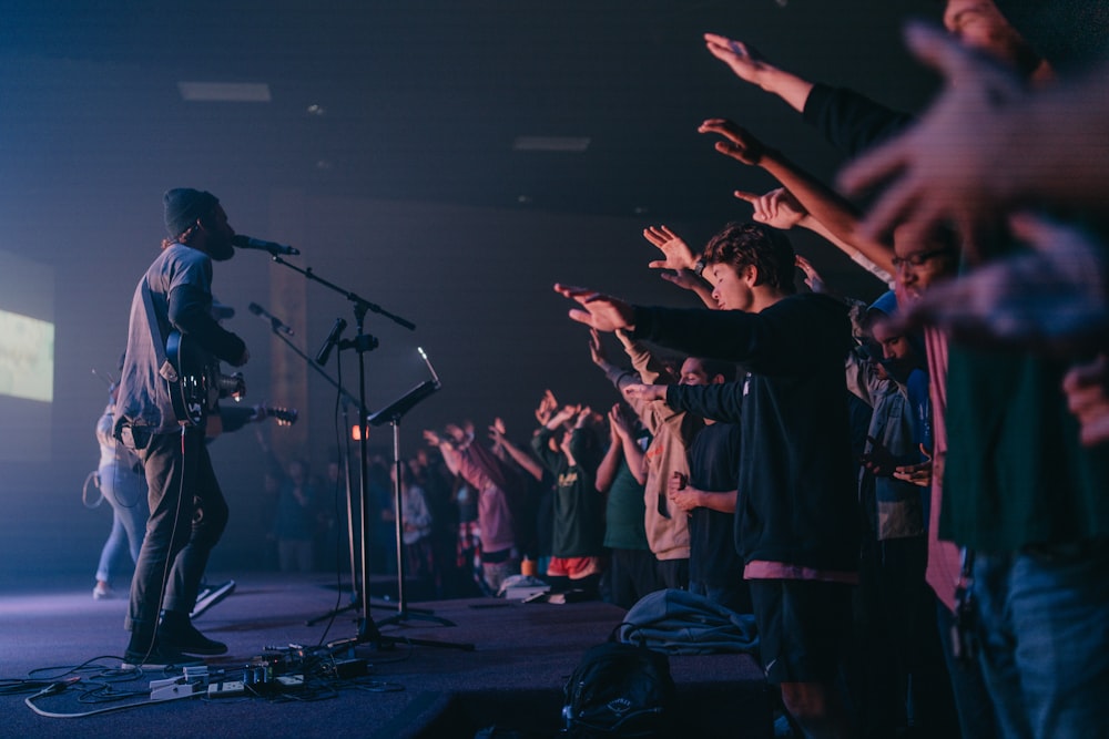 man playing guitar singing in front of crowd