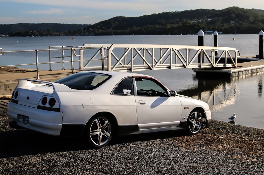 parked white coupe on shore beside dock