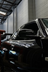 Polished black car reflecting the workshop lights perfectly.