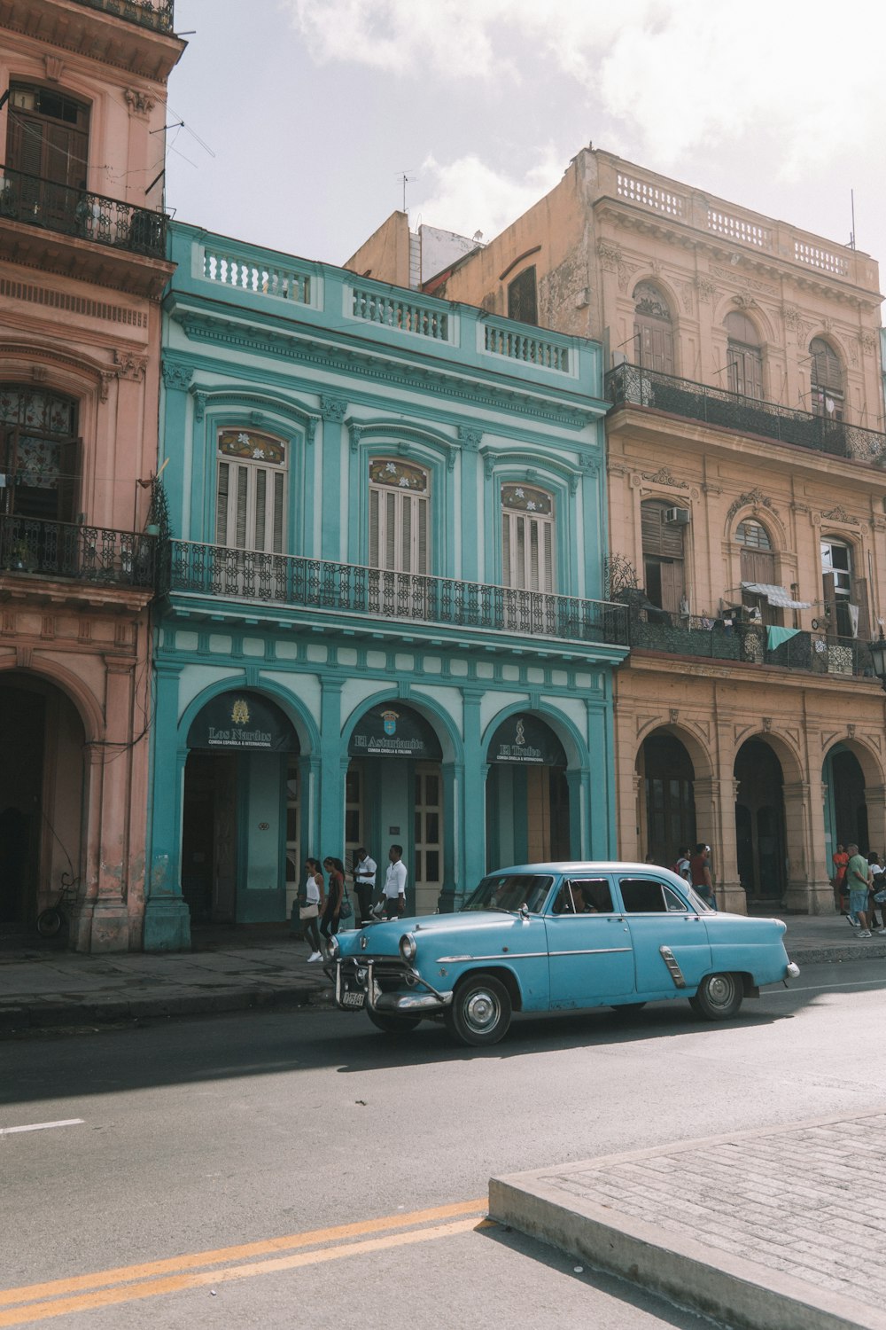 teal sedan beside teal building