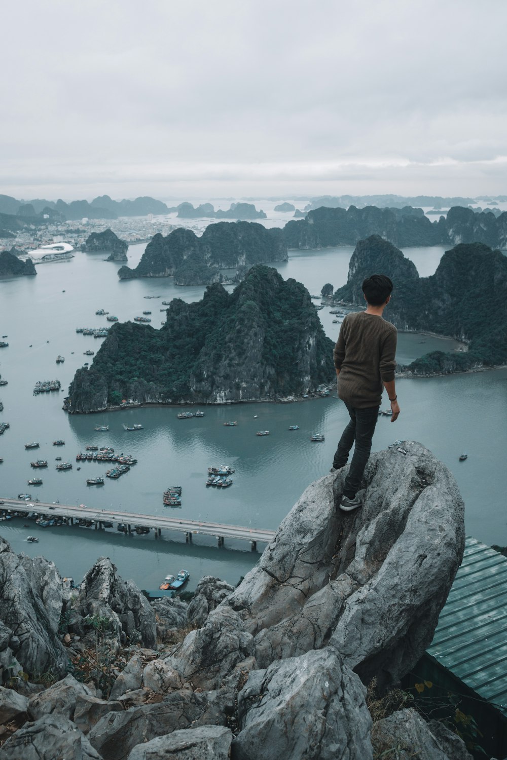 man standing on top of a rocky mountain overlooking other islets
