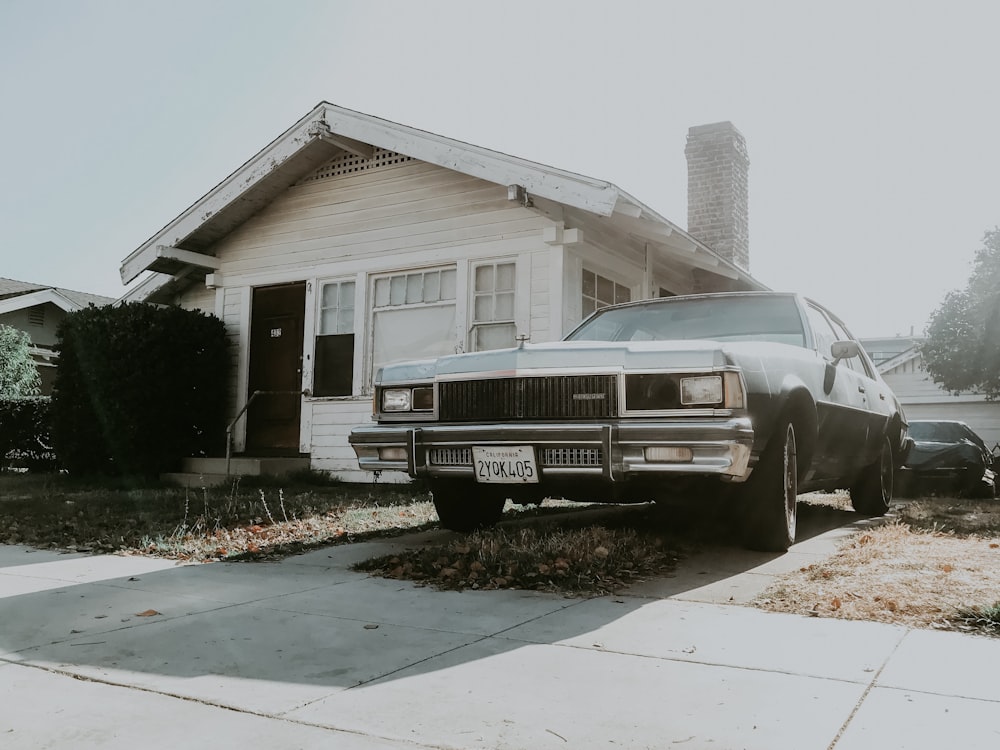 black sedan parked beside house