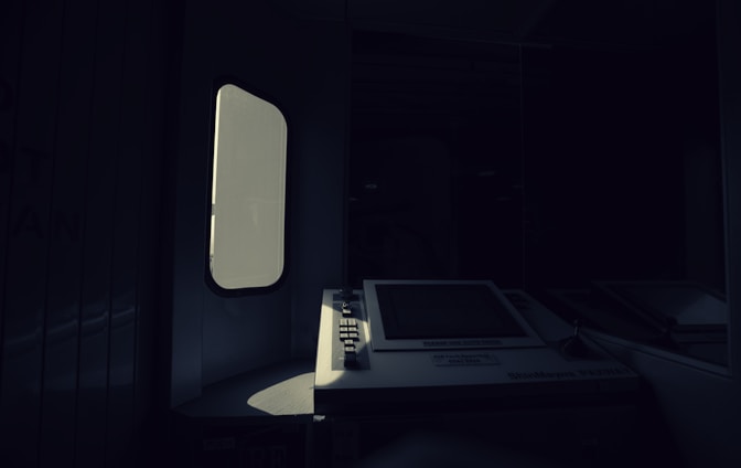 A dimly lit interior with a vintage ATM or ticket machine partially illuminated by light entering through a nearby window. The shadows create a stark contrast between the bright screen and the surrounding darkness.