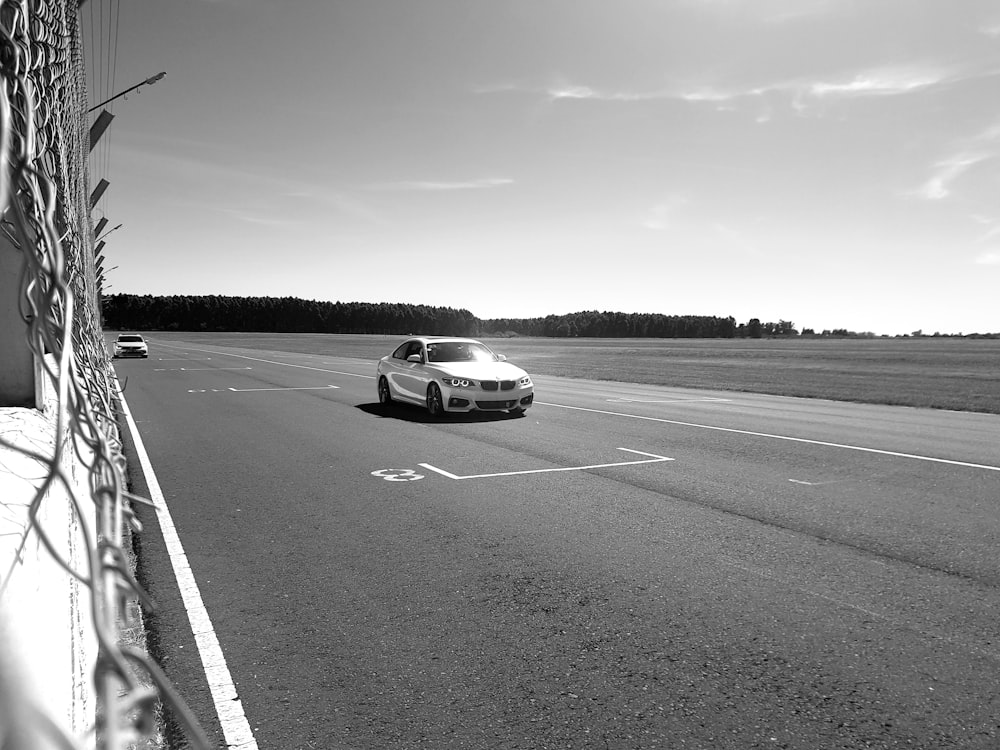 grayscale photography of coupe on road