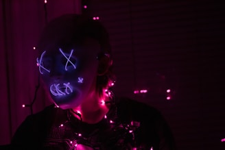 a woman wearing a neon mask in a dark room