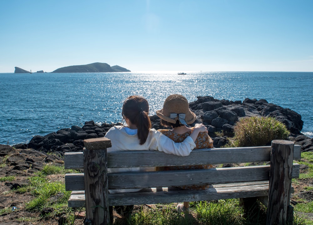 two girl sitting on bench during daytime