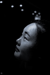 Portrait of a woman with soft natural light highlighting her thoughtful expression against a neutral background.