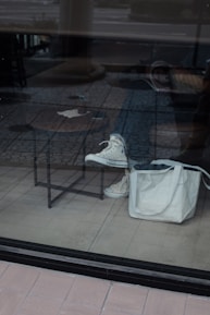 Close-up of a trendy sneaker paired with a chic handbag on a wooden table.