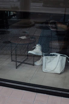 A pair of comfortable flat shoes placed beside a casual handbag on a cozy floor.