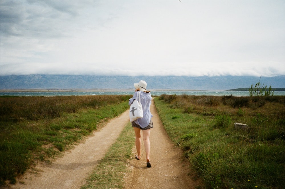 woman walking between green grasss