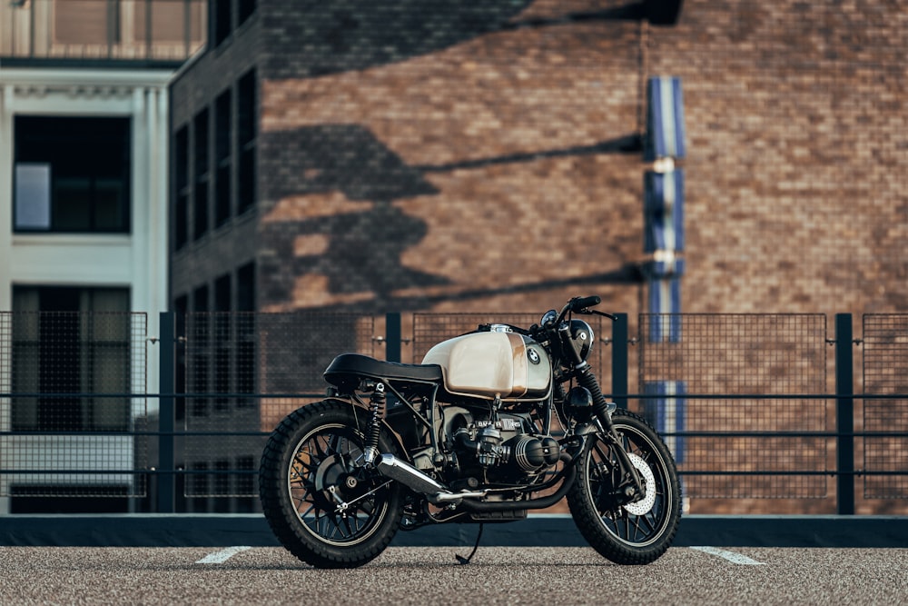 black and white cafe racer motorcycle parked beside wall