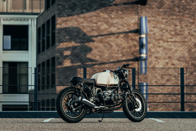 A classic BMW café racer motorcycle parked against a brick building