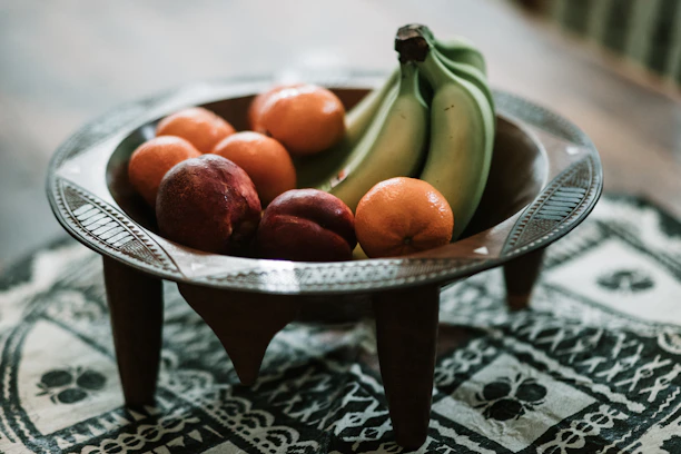 Close-up of a vibrant stoneware bowl filled with fresh fruit on a wooden table.