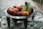 Close-up of a rustic handmade ceramic bowl filled with fresh fruit on a wooden table